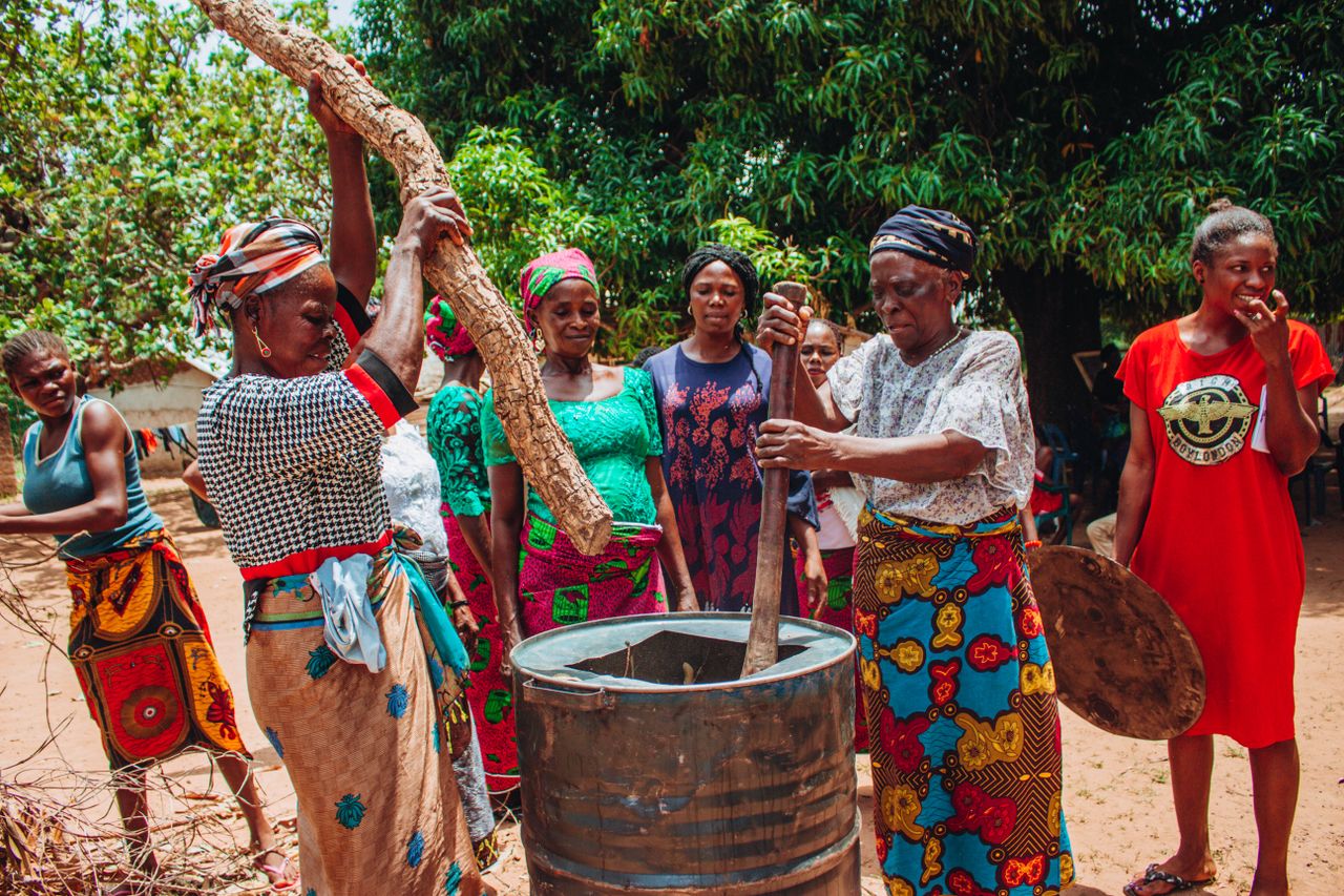 services-02 Group of women in colorful traditional clothing cooking outdoors.